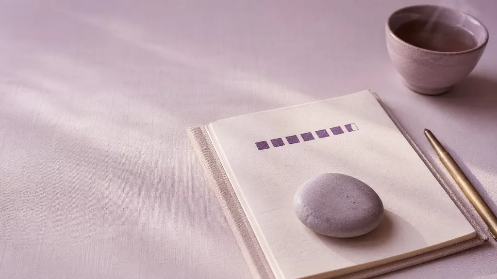 Notizbuch mit Streak-Fortschritt, Stein und Tee auf sanftem Lavendel-Hintergrund